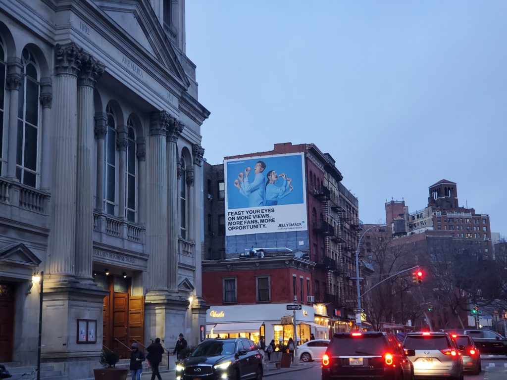 On of the billboards of Julie Goolia and JP Lambiase of Hellthy Junk Food in the Greenwich Village of New York City as part of Jellysmack's out-of-home advertising campaign