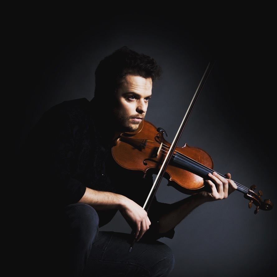 Rob Landes holding a violin against a grey background