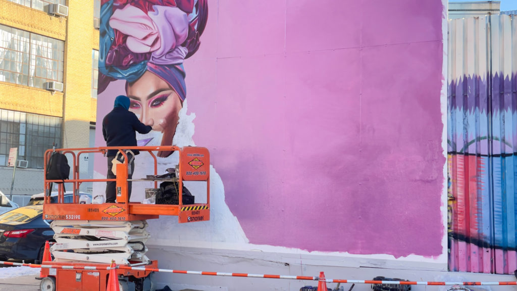 A muralist paints creator Patrick Starrr on a building wall in the SoHo neighborhood of New York City.