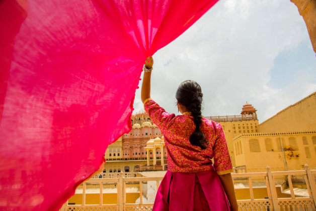 Woman in front of the Hawa Mahal, also known as the Palace of the Wind, in the pink city of Jaipur in Rajasthan, India.