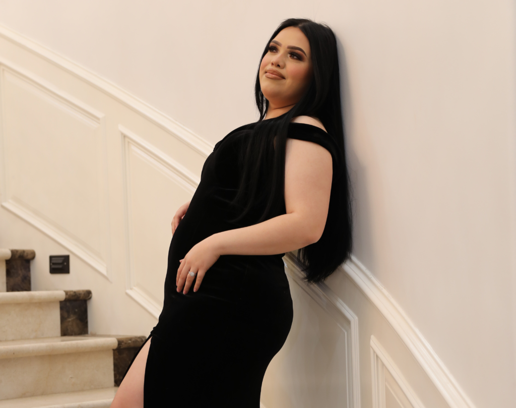 Karina Garcia stands on a staircase wearing long black gown.