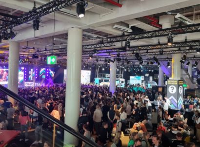 Crowd of people in a large room with lights and colorful screens at OMR Festival.