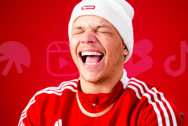 Creator SpicyyCam smiling with mouth open on a red background with social media logos.