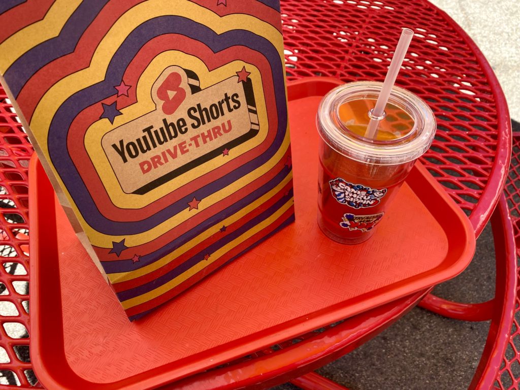 A close up image of a YouTube Shorts branded fast-food lunch bag and drink. 