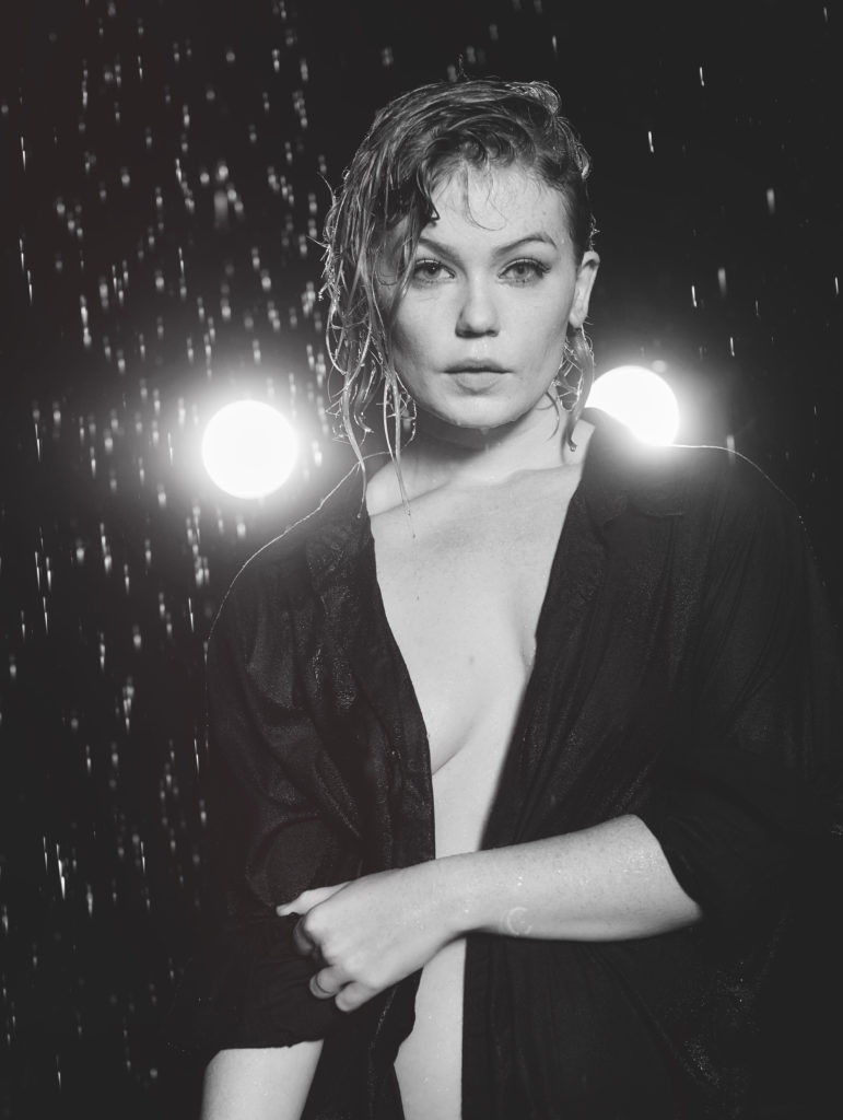 black and white photo of Jo Steel in the rain with headlights behind them