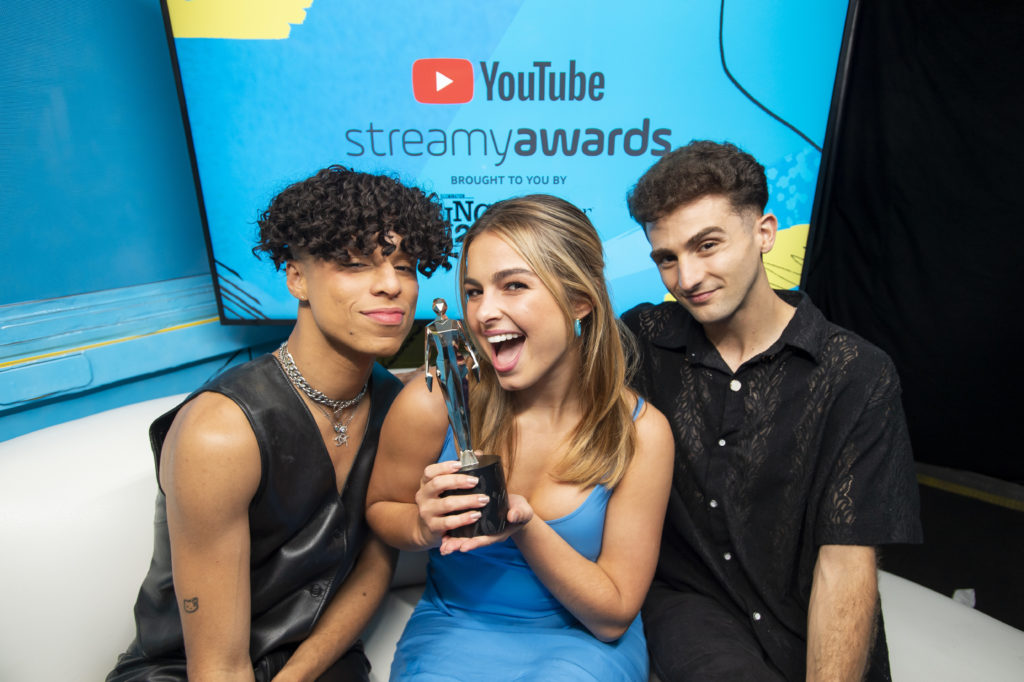 Creator Addison Rae holds her 2021 Streamy Award while sitting between ceremony hosts Larray and Issa Twaimz.