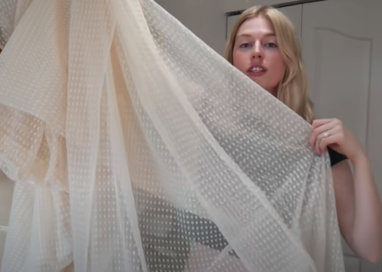 Creator Jenna Phipps holds up white sheer polka dot fabric 