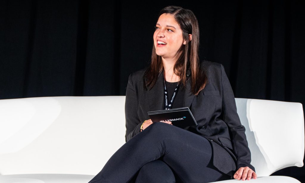 Cat Valdes, Jellysmack Sr. Director of Partnerships, smiling and staring to her right while sitting on a couch on stage at VidCon 2022