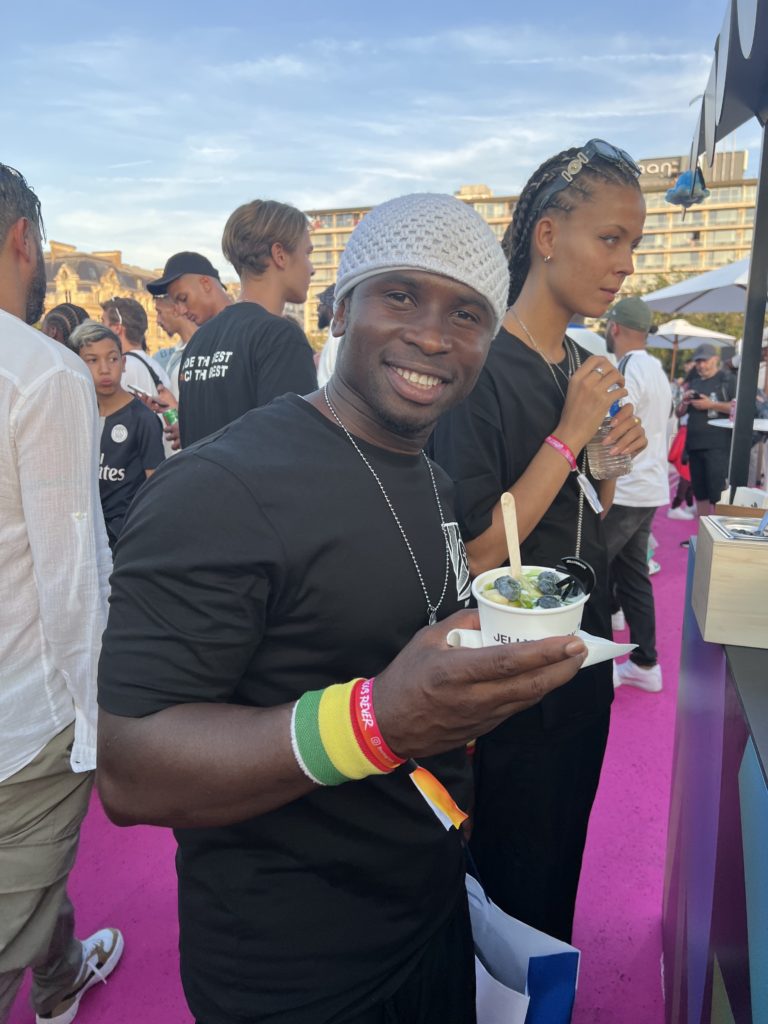 Iya Traoré, top Montmartre street footballer, smiling holding a bowl of frozen yogurt.