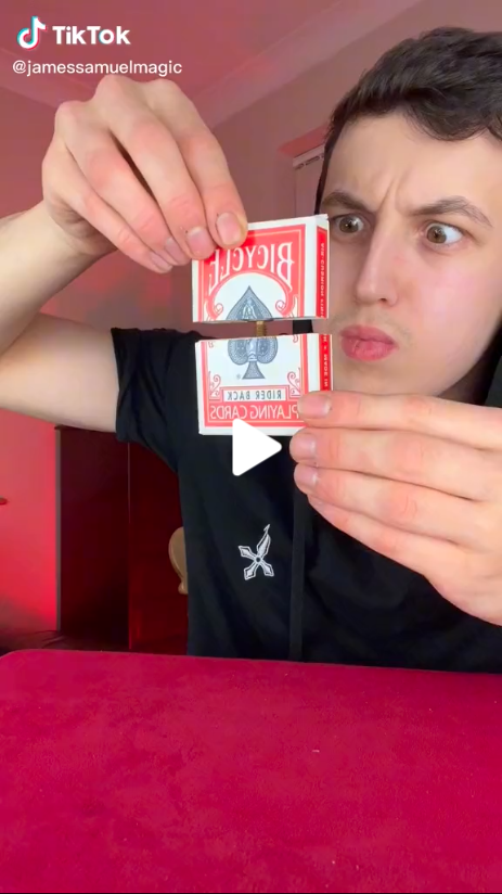 TikTok magician James Samuel looks confused as he screws together a wooden box decorated like a box of playing cards