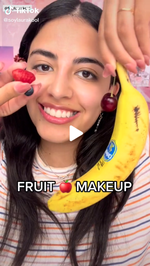 Creator SoyLauraKool smiling holding up a strawberry, grape and banana with the text FRUIT MAKEUP