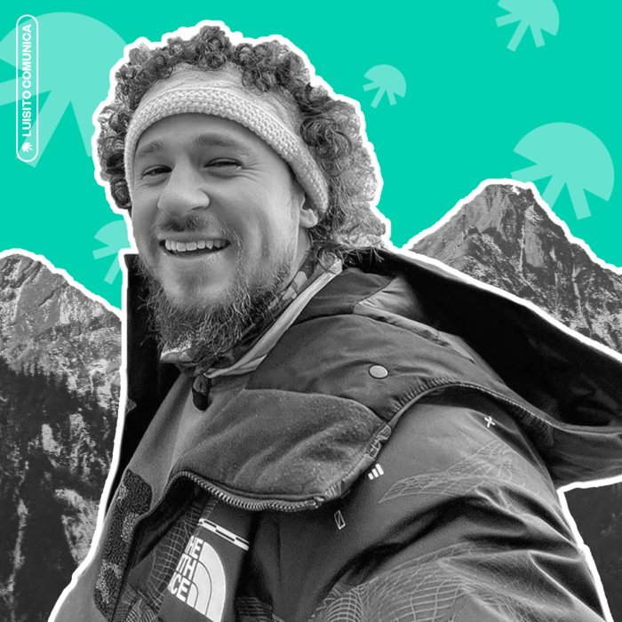 Creator Luisito Comunica in black and white wearing a jacket in front of mountains with a teal jellyfish patterned background