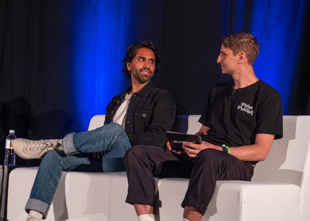 Creators Colin and Samir sitting on a white couch looking at each other on stage at VidCon 2022