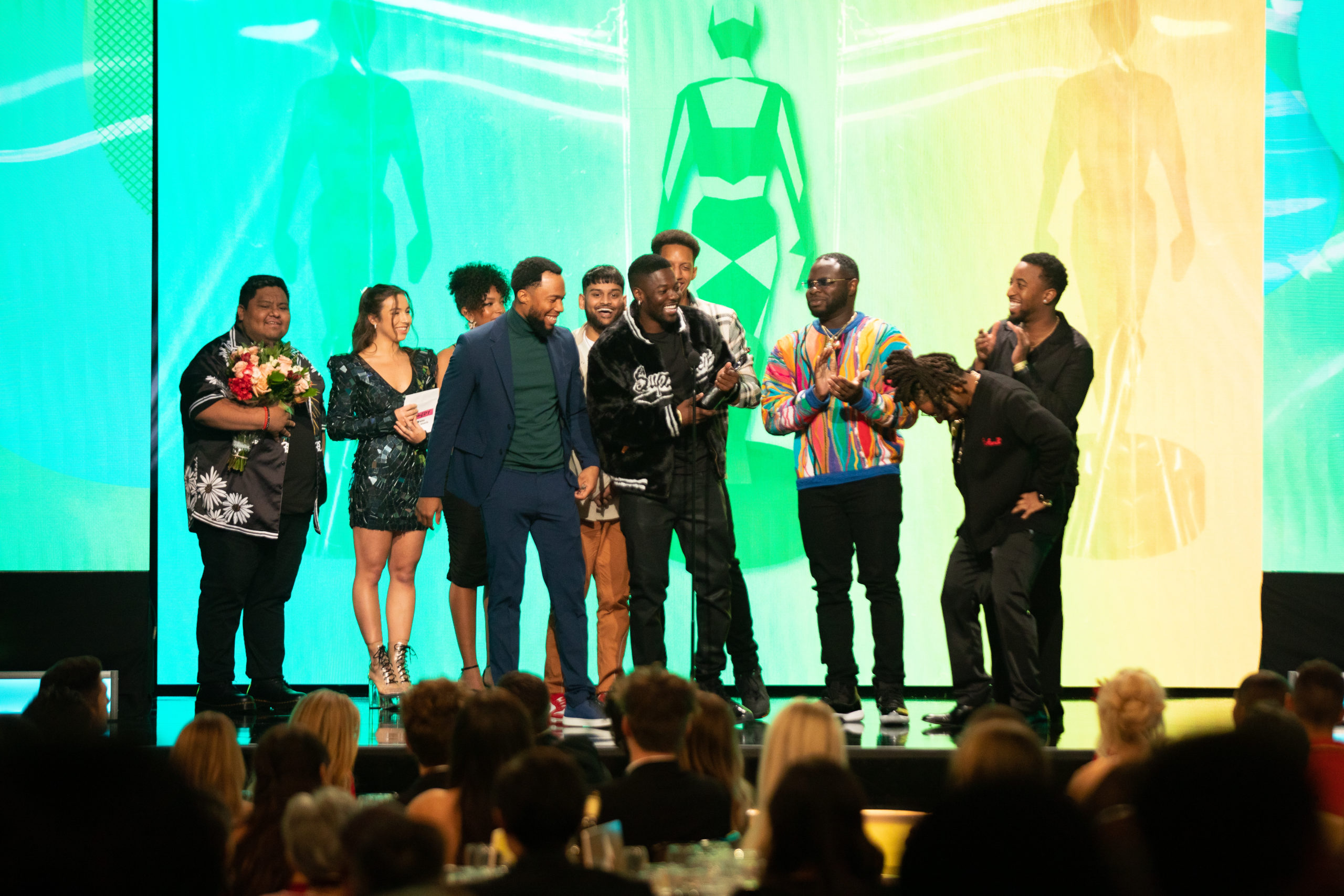Group of men accept an award on stage with green background.