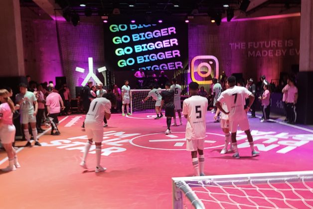 Soccer players on a pink and orange indoor pitch with an Instagram logo and Jellysmack's Go Bigger tagline in the background.