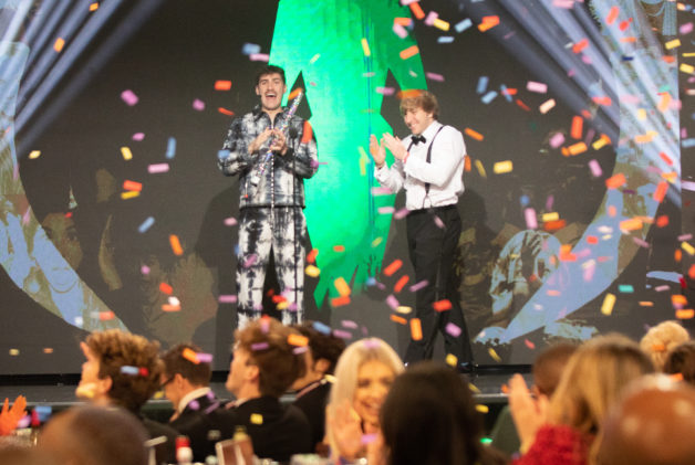 Creator Airrack and friend standing on stage smiling and clapping while confetti is coming down